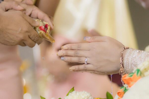 Die Nägel der Braut sind mit Glitzer-Nagellack verziert. Die Hände werden mit Wasser übergossen.