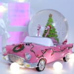 In einem pinken Spielzeugauto ist eine Schneekugel mit zwei Flamingos und einem Weihnachtsbaum montiert