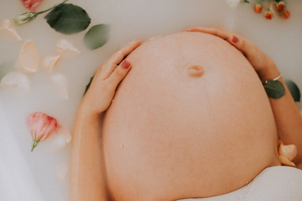 Eine Schwangere nimmt ein milchiges Bad mit Blumen darin