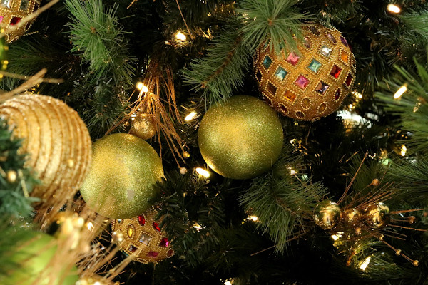 An einem Weihnachtsbaum hängen verschiedene Kugeln, die mit Glitzer verziert wurden