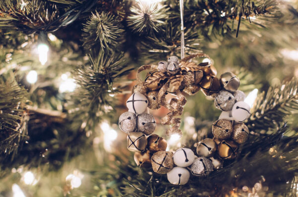 Ein Weihnachtskranz aus glitzernden Glocken hängt an einem Tannenbaum