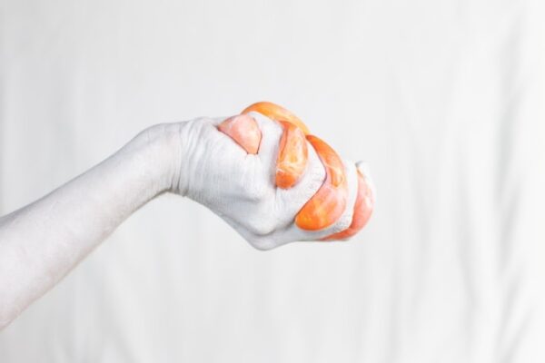 Eine weiße Hand hält einen Klumpen orangenen Schleim in der Hand