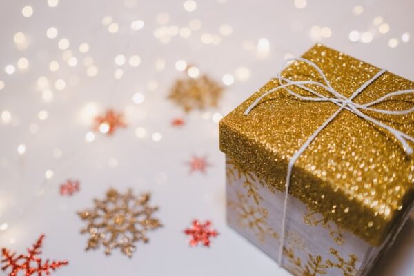 Eine kleine Kiste mit einem gold glitzernden Deckel, daneben ausgeschnittene Schneeflocken und Sterne