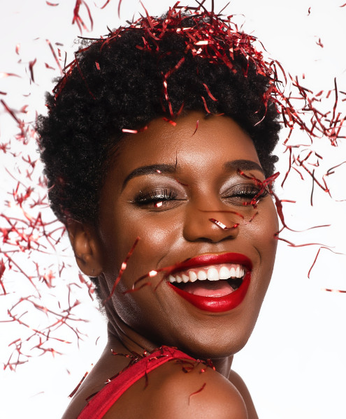 Ein Frau mit rotem Lippenstift und glitzerndem Make-up auf die rotes Konfetti rieselt